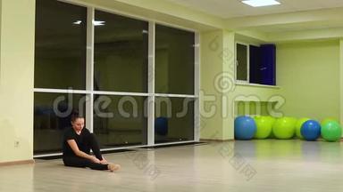 穿黑色运动服的可爱女孩<strong>艺术体操</strong>运动员，穿着尖鞋坐在运动健身房里